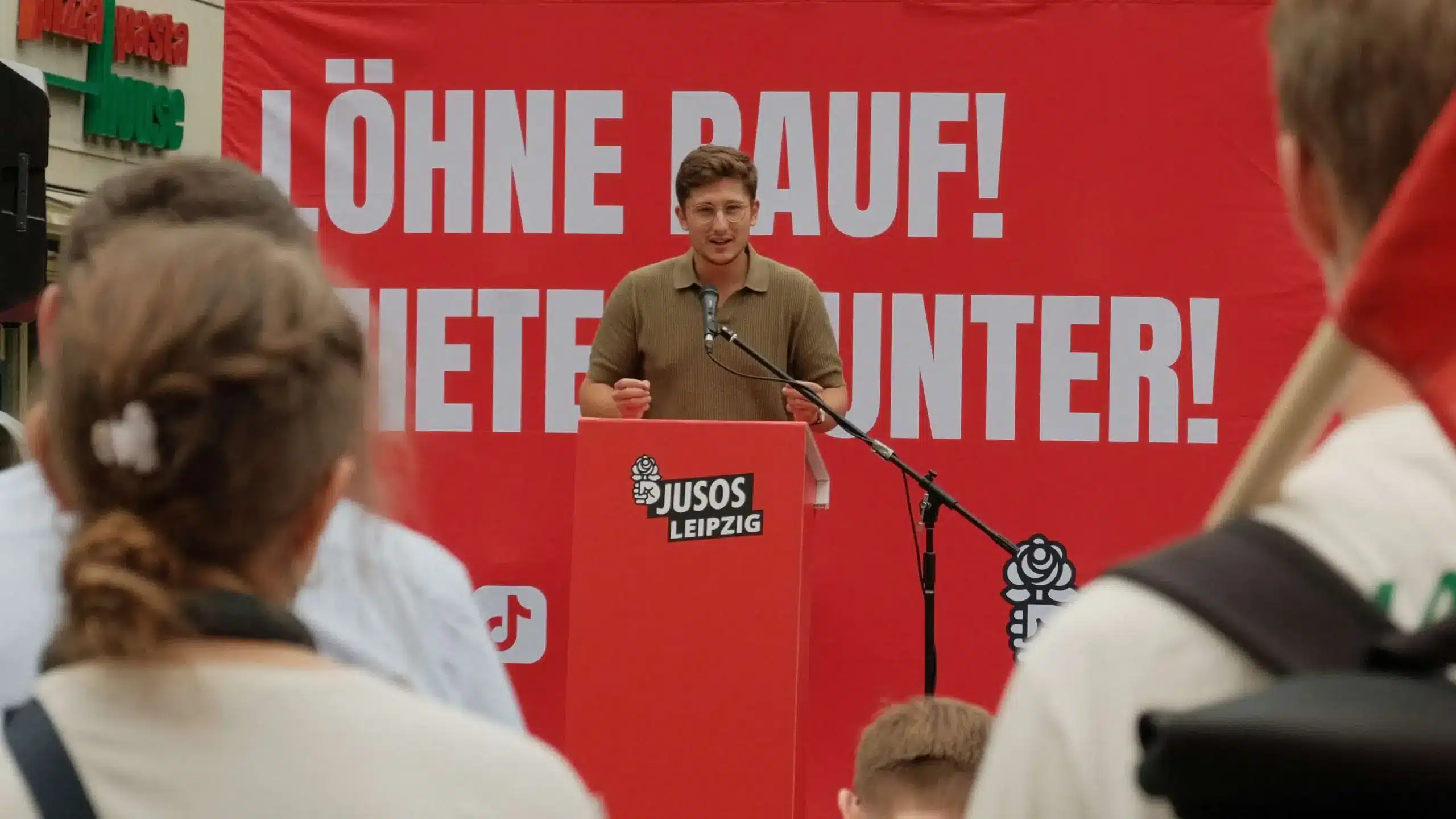 Juso-Chef Philipp Türmer hät eine Rede. Hinter ihm steht auf einem Banner "Löhne rauf! Mieten runter!".